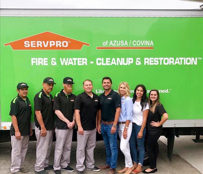 Eight SERVPRO employees with the men in uniforms lined up in front of the side of a SERVPRO box truck